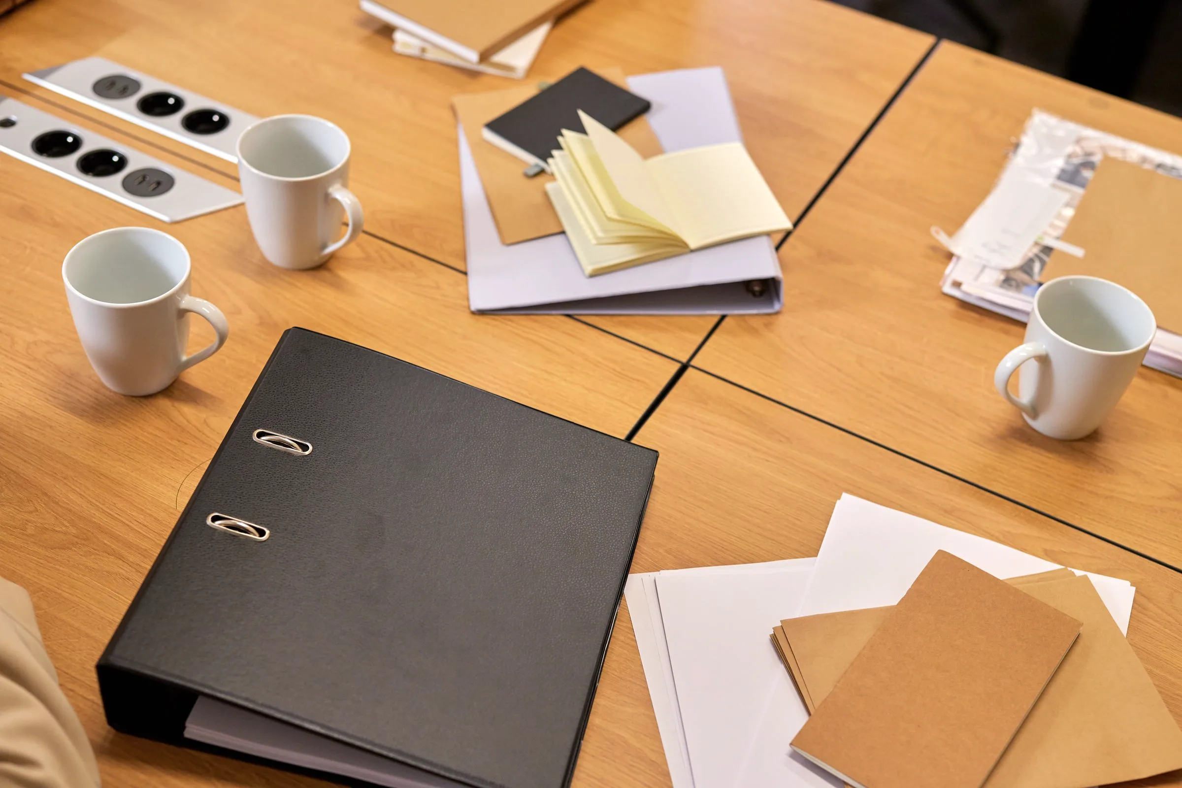 A black ring binder and open notebooks on a meeting table, ready for review.