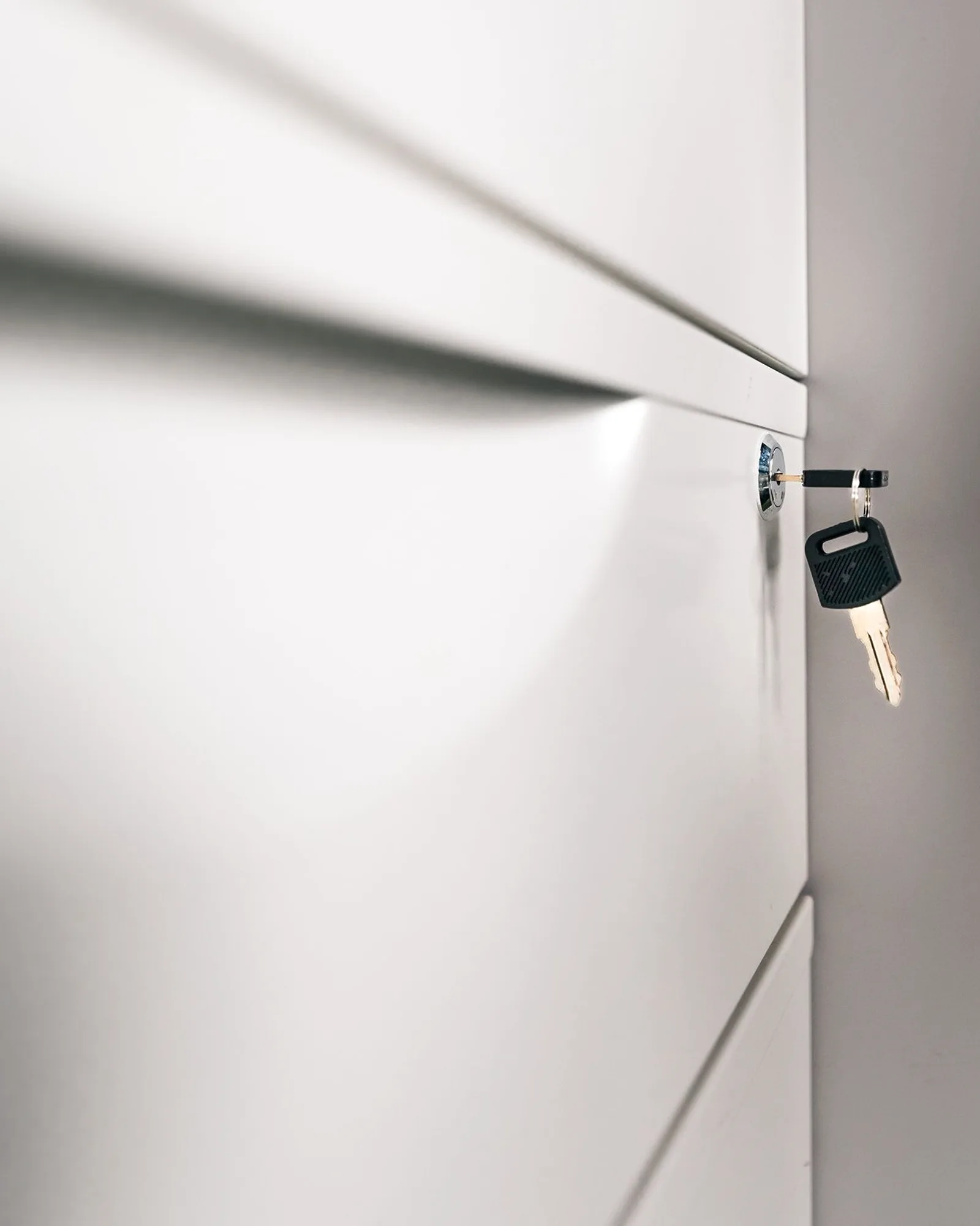 A key in the lock of a light grey office storage cabinet.
